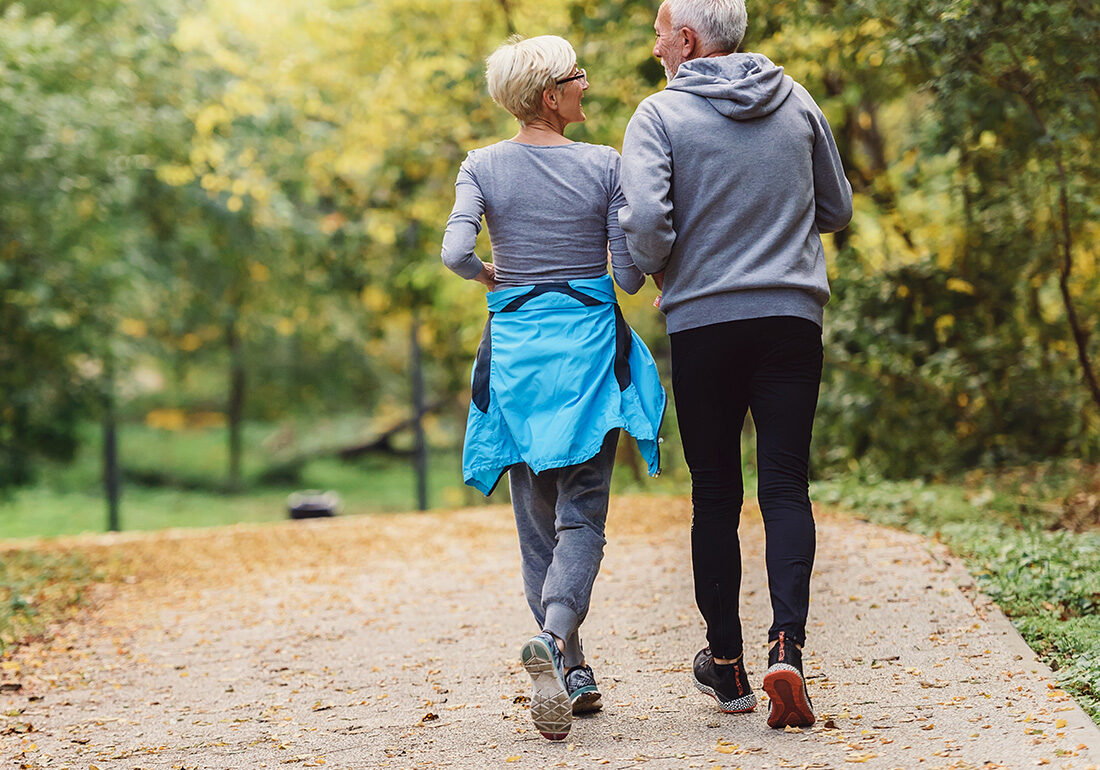 Cheerful active senior couple jogging in the park. Exercise toge